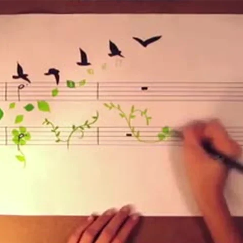 Hands drawing birds and flowers on sheet music